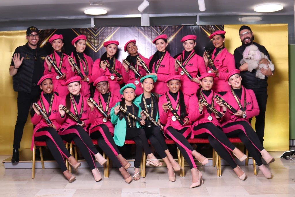 Graduación de la Promo Magenta en academia de modelaje en Caracas con modelos posando en pasarela con diplomas y los directores de la academia